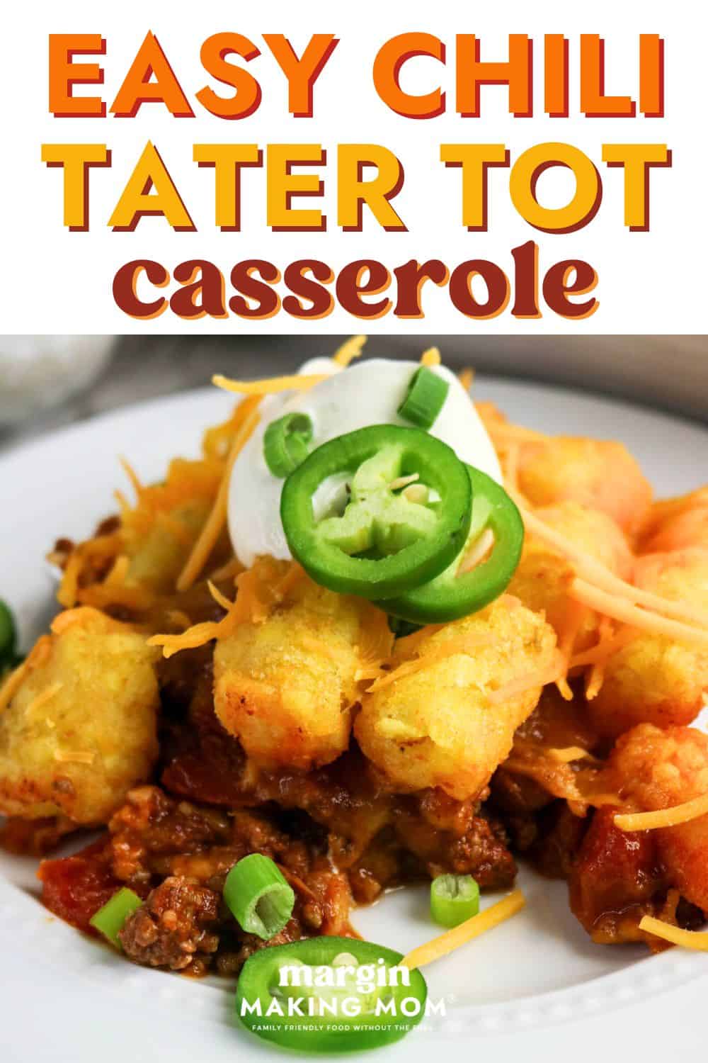 close-up view of easy chili tater tot casserole served on a white plate, garnished with peppers, onions, and sour cream.