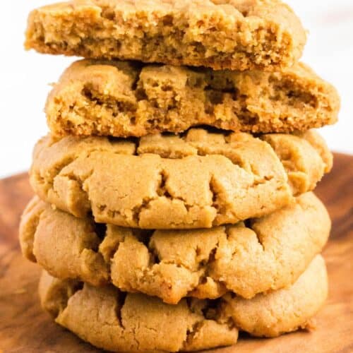 a stack of easy flourless peanut butter cookies that can be made with or without chocolate chips. The top cookie has been broken in half to show the chewy interior.