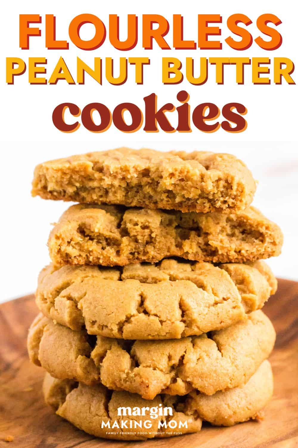 stack of flourless peanut butter cookies on a wooden plate. The top cookie has been broken in half to show the soft and chewy texture of the cookies.