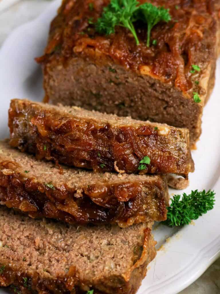 French onion soup meatloaf, partially sliced, served on a white platter.