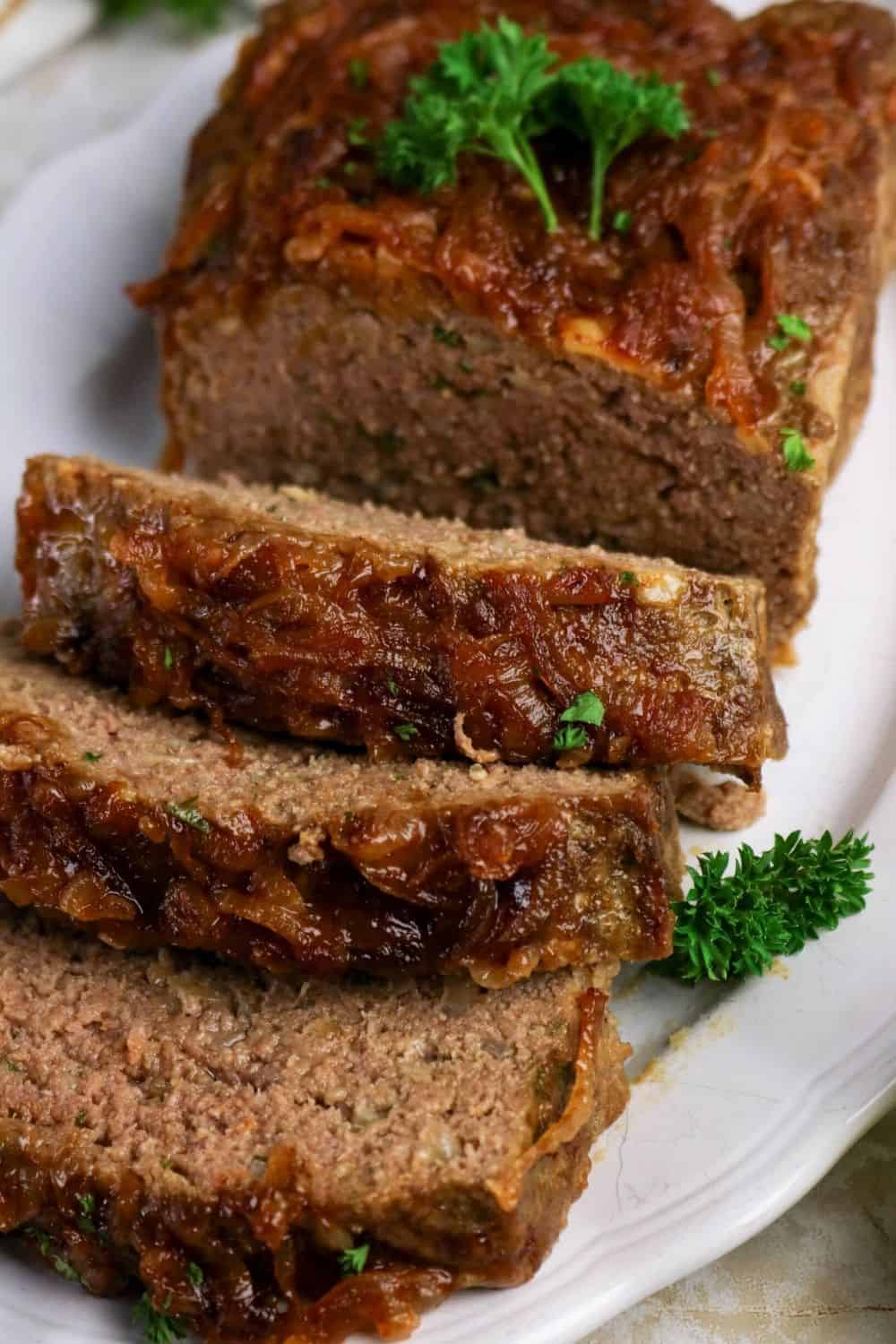 Partially sliced loaf of Lipton onion soup mix meatloaf on a white platter.