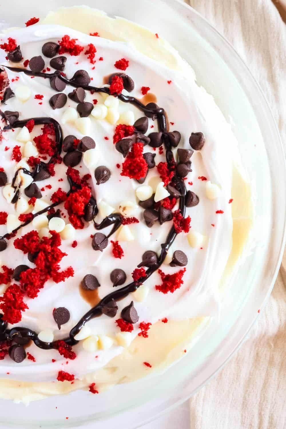 Overhead view of the top surface of red velvet cake trifle, complete with chocolate sauce, chocolate chips, and cake crumbles.