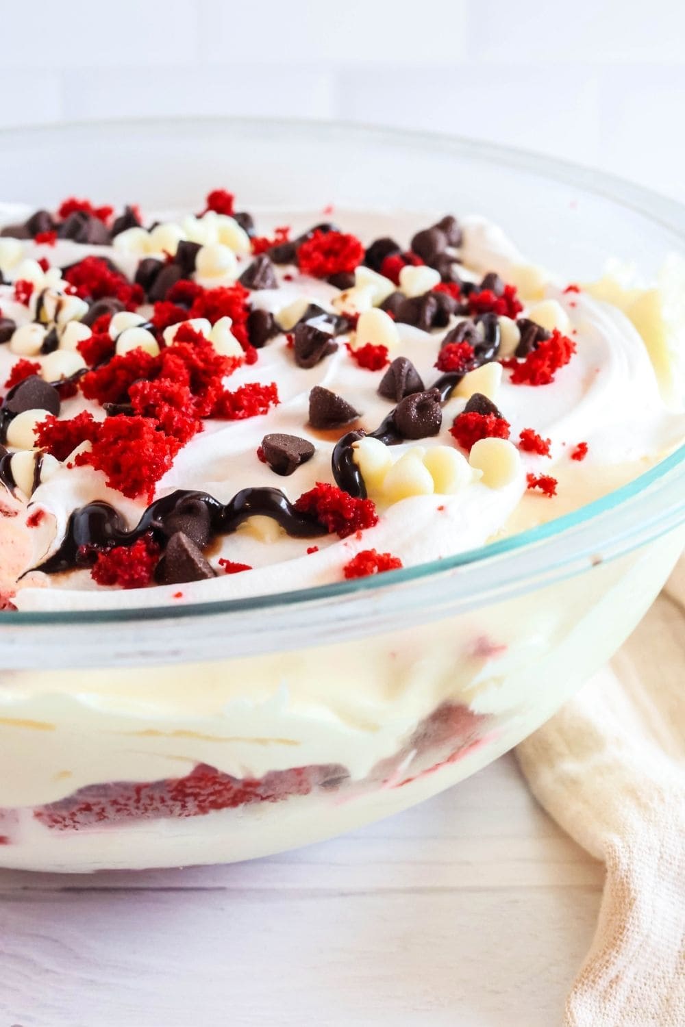 Side view of a glass trifle bowl showing the layers of red velvet cake and creamy pudding filling.