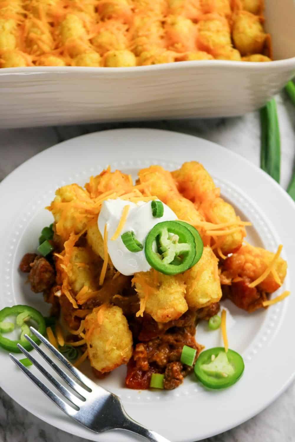 a serving of tater tot casserole with chili on a white plate with a fork.