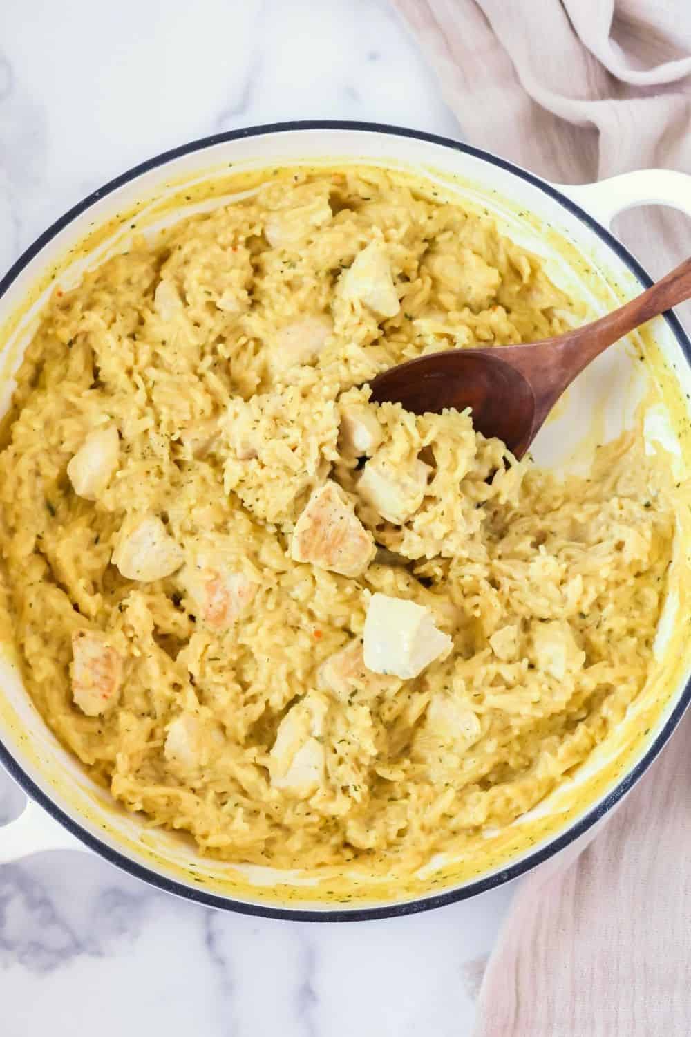 overhead view of a large skillet of casserole made with Knorr rice and chicken. A woden spoon is in the dish.