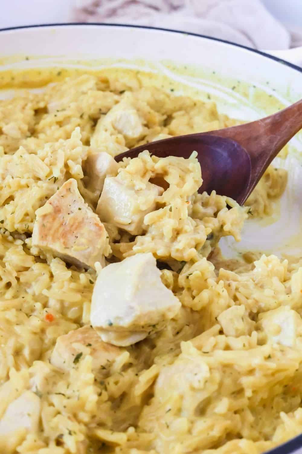 close-up view of creamy Knorr chicken and rce with a wooden spoon scooping out a helping.