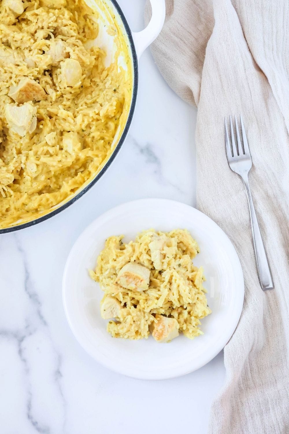 overhead view of a white plate with shortcut chicken and rice served on it, with the skillet of remaining casserole in the background.