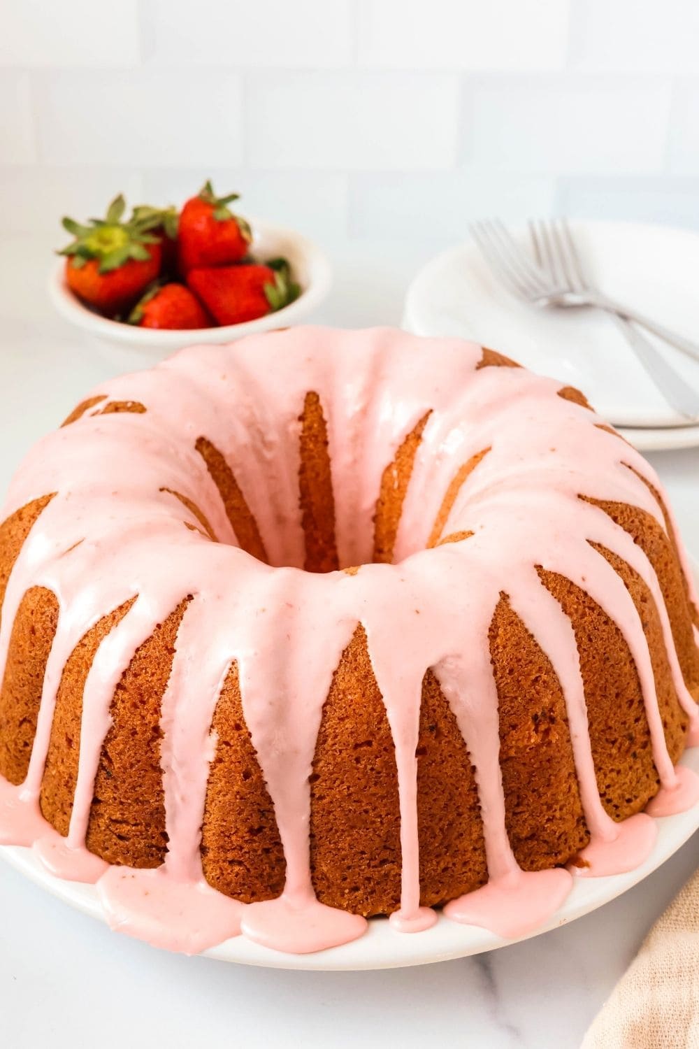 Cake mix strawberry pound cake topped with glaze and served on a white plate.