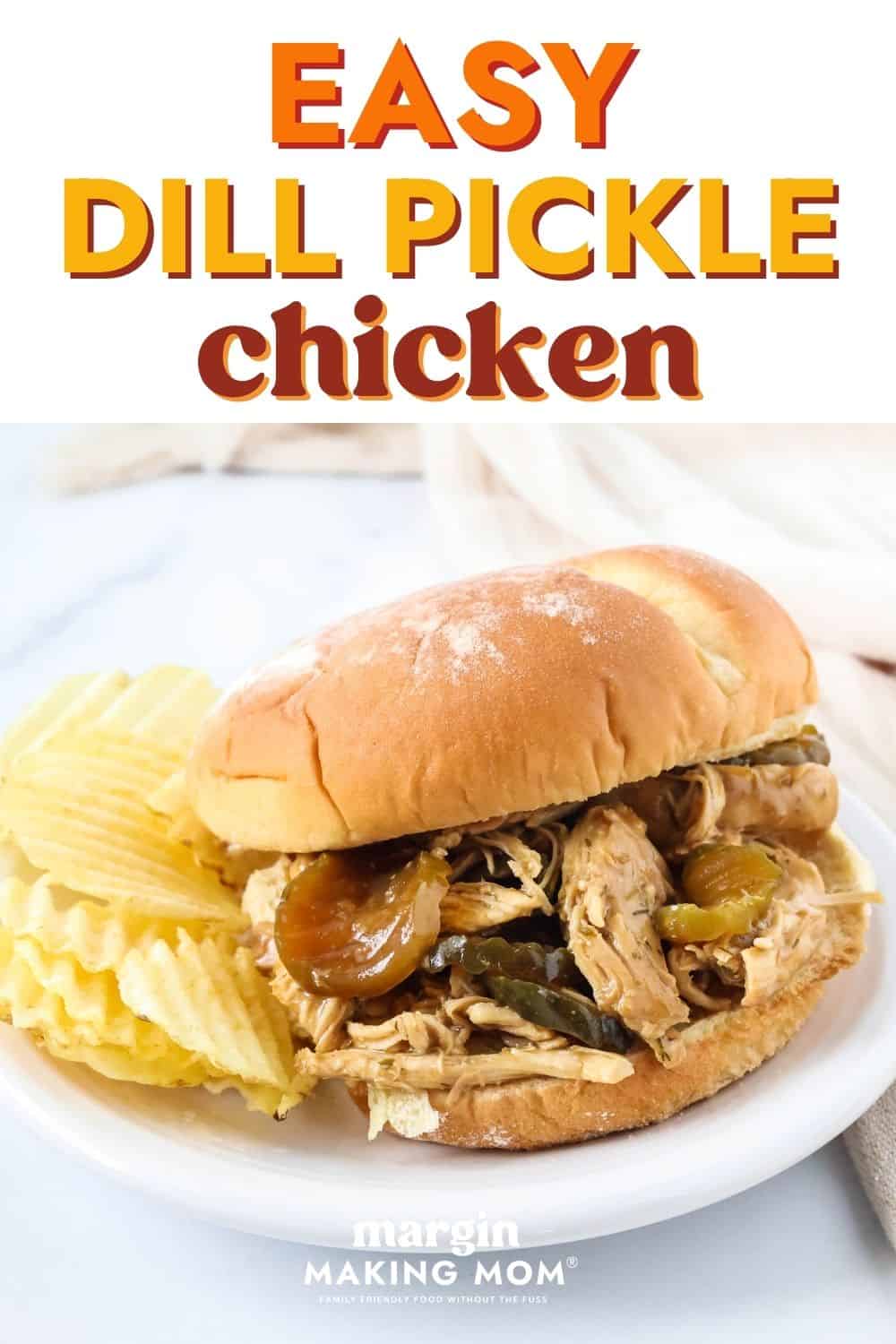 Dill pickle chicken on a sandwich bun, served on a white plate alongside potato chips.