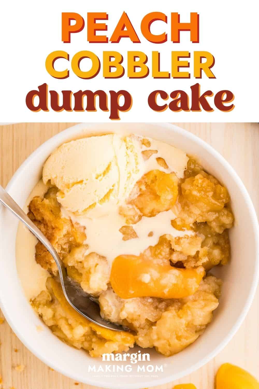 overhead view of a serving of warm peach cobbler dump cake topped with melting vanilla ice cream in a white bowl with a spoon.