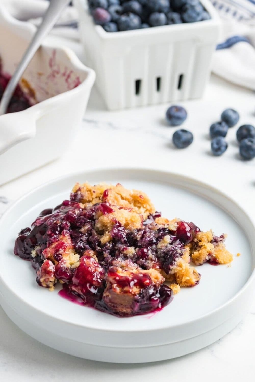 a serving of warm blueberry dump cake on a white plate.