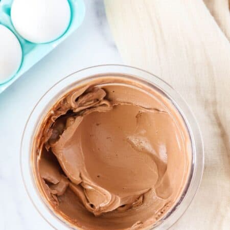 hard boiled egg ice cream, in chocolate flavor, in a clear container. A carton of eggs is in the background.