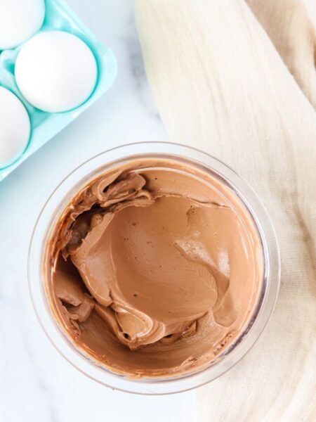 hard boiled egg ice cream, in chocolate flavor, in a clear container. A carton of eggs is in the background.