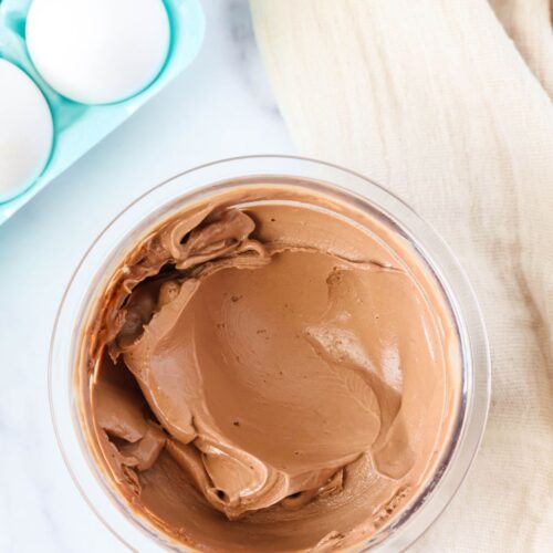 hard boiled egg ice cream, in chocolate flavor, in a clear container. A carton of eggs is in the background.