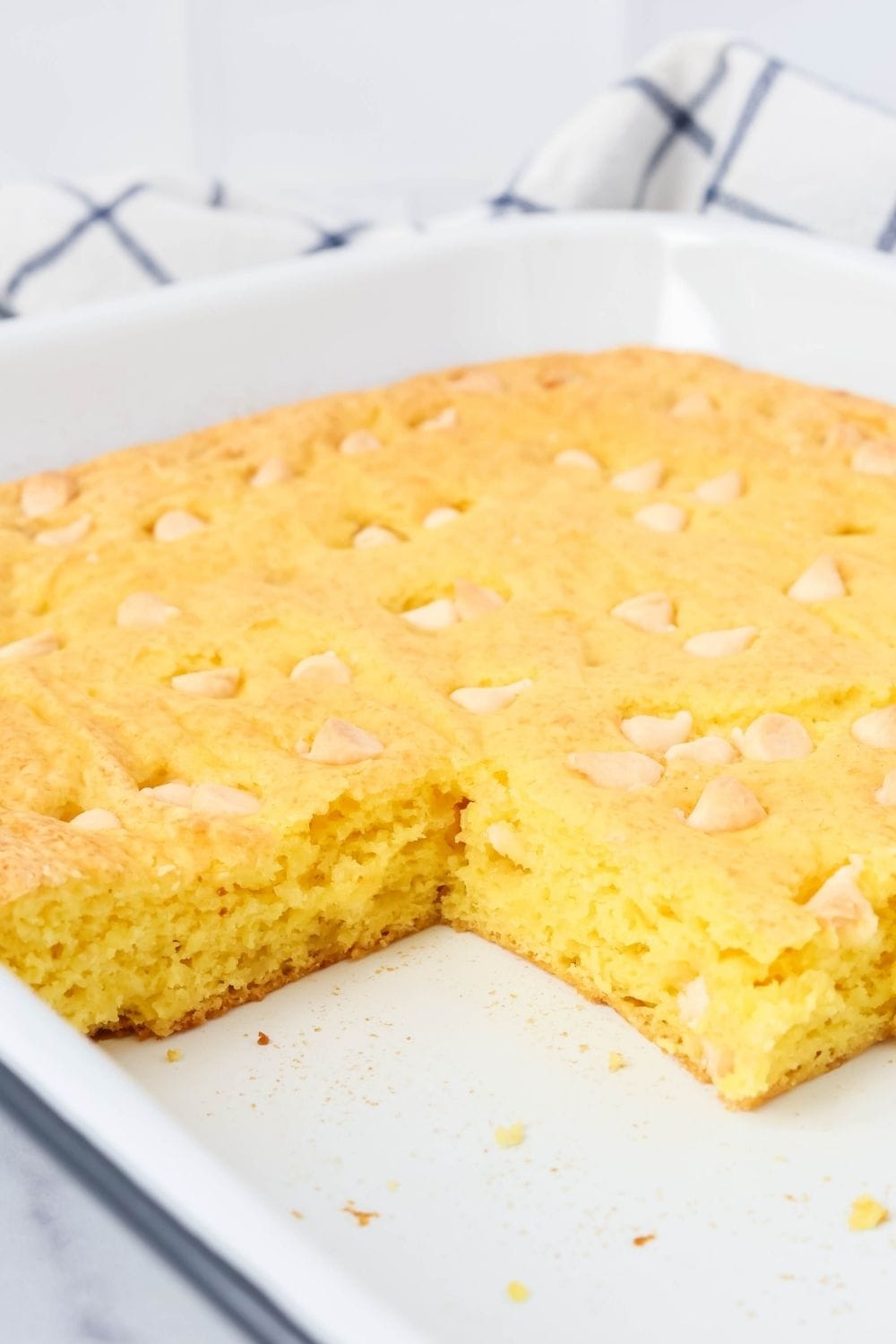 pan of lemon pudding cake bars, with some of the bars removed from the pan, showcasing the moist interior of the cake.