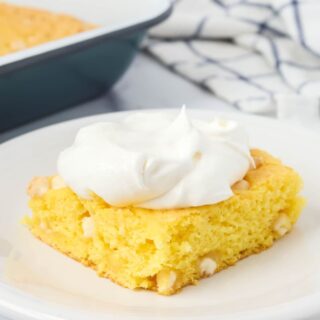 Slice of lemon pudding dump cake served on a white plate, garnished with whipped topping.
