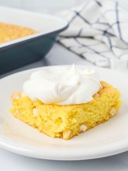 Slice of lemon pudding dump cake served on a white plate, garnished with whipped topping.