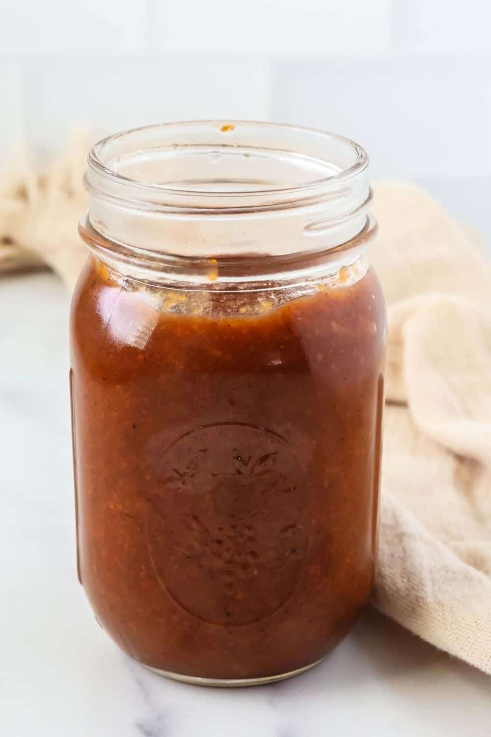 side view of a mason jar filled with no-peel peach butter.