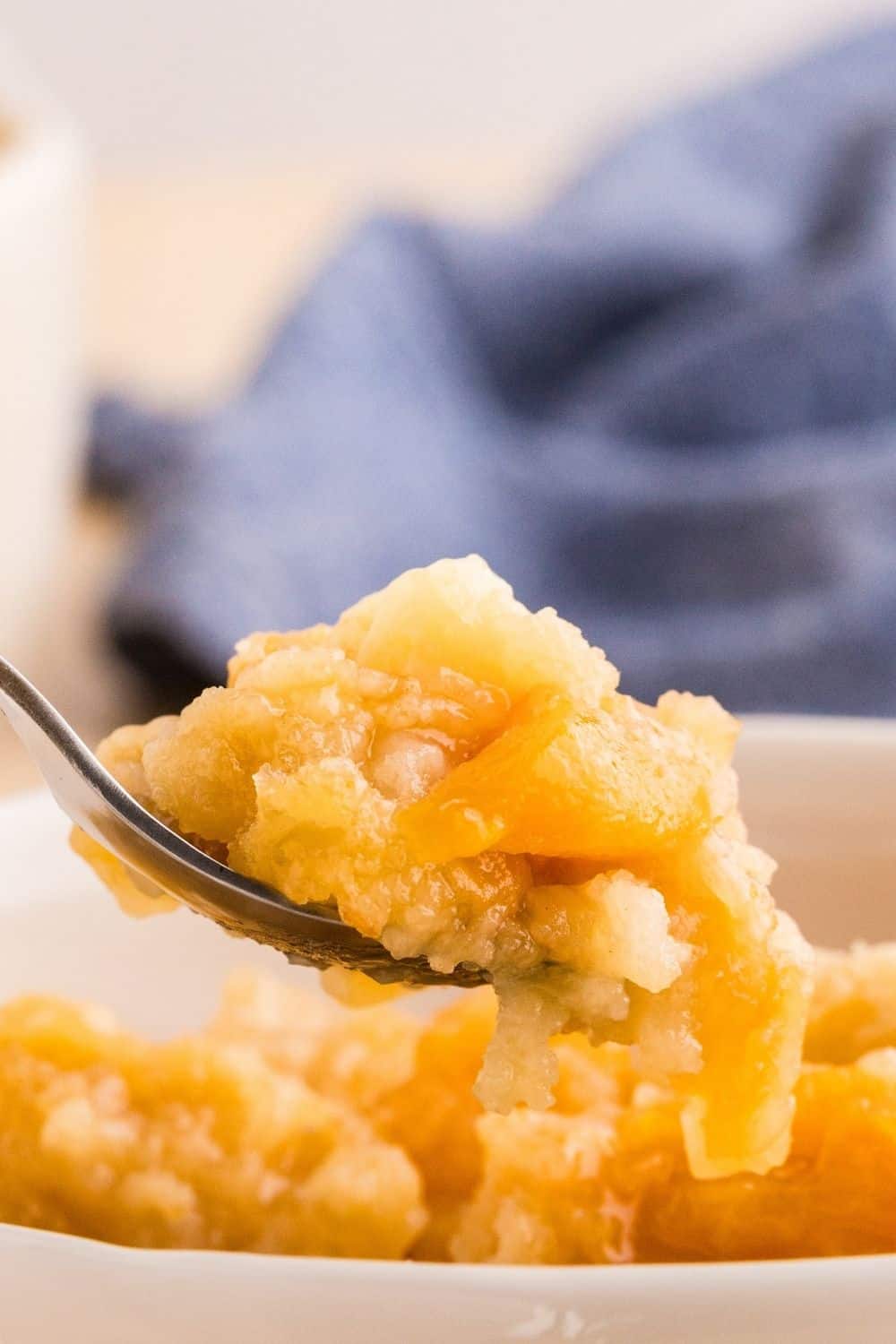 Close up view of a spoon that lifts out a bite of peach dump cake made with canned peaches.