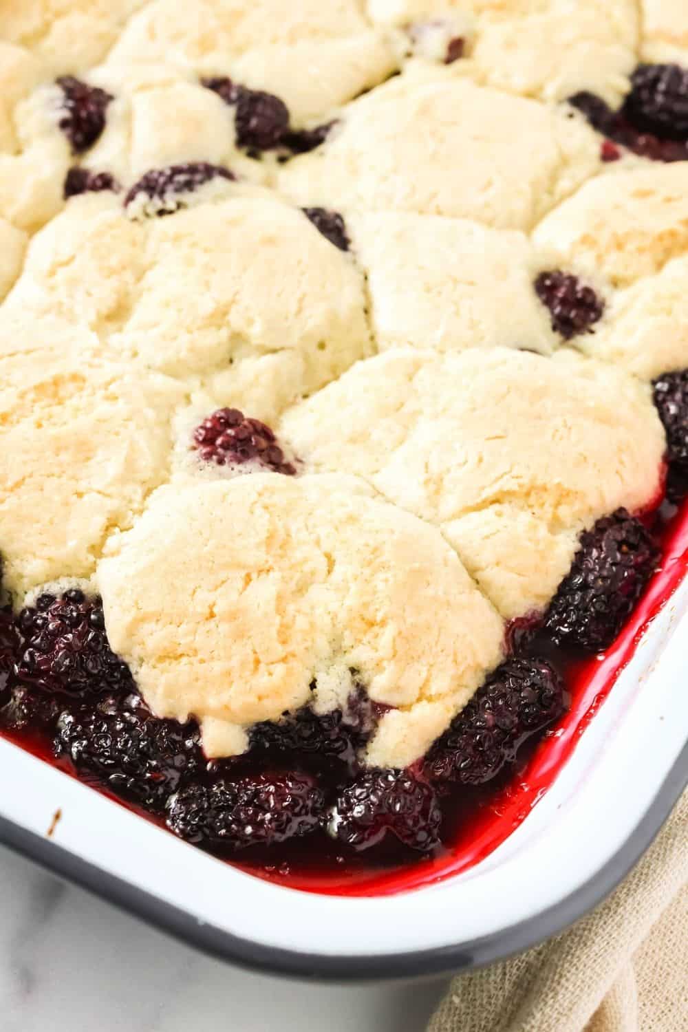 close-up view of part of a pan of freshly baked blackberry cobbler in a baking dish.