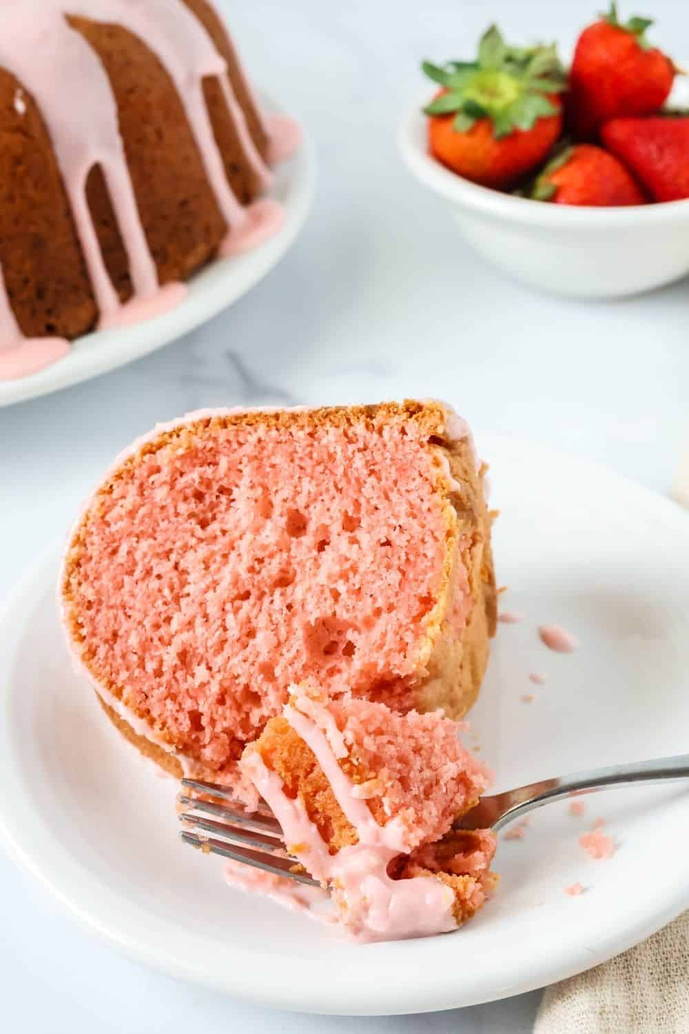 a fork cuts a bite out of strawberry bundt cake from a strawberry cake mix