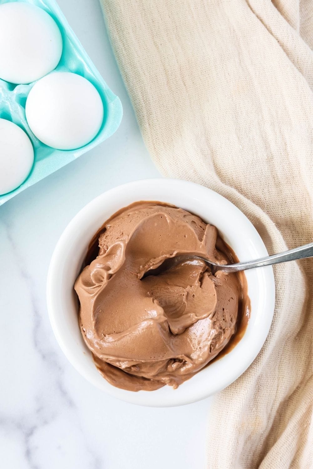 overhead view of a small white bowl of creamy chocolate ice cream made with leftover hard boiled Easter eggs.