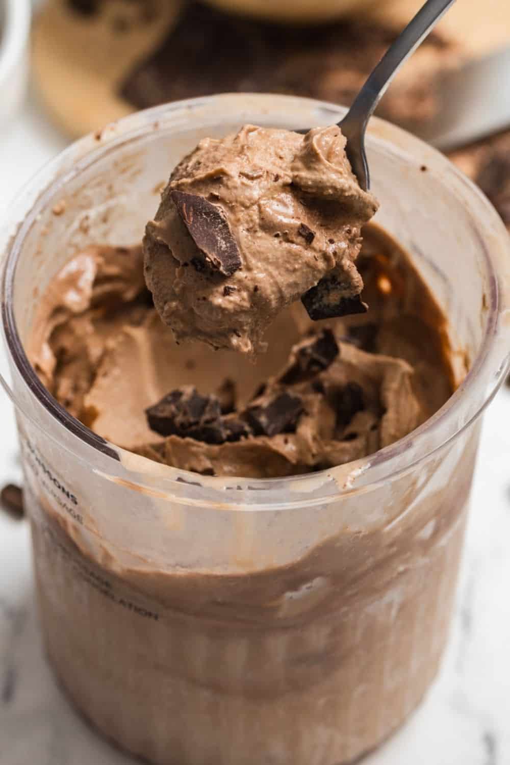 a spoon lifts a bite of coffee ice cream made with espresso powder from the Ninja Creami pint container it's stored in.