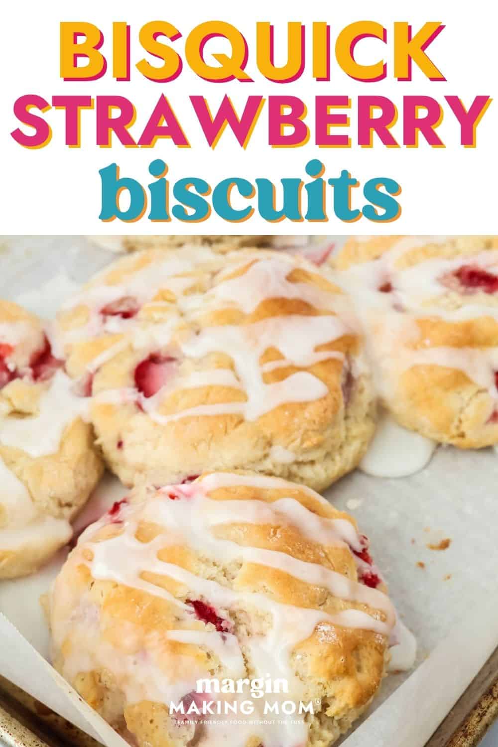 Bisquick strawberry biscuits, topped with icing, on a parchment-lined baking sheet.