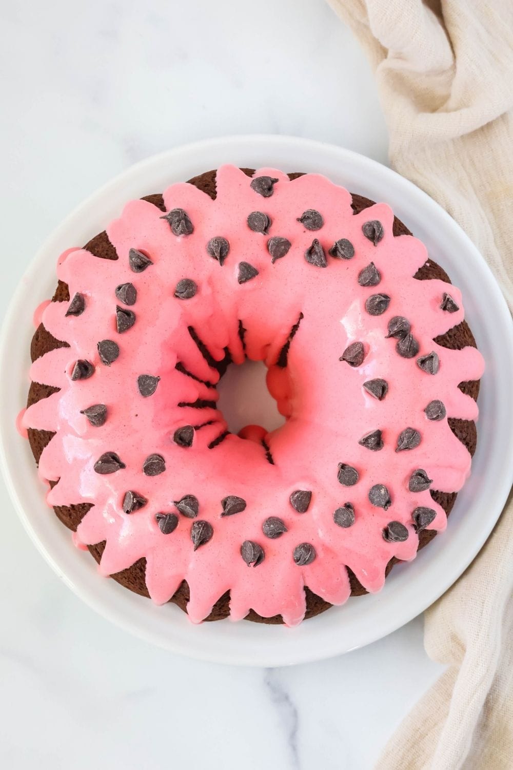overhead view of a chocolate strawberry bundt cake on a white plate.