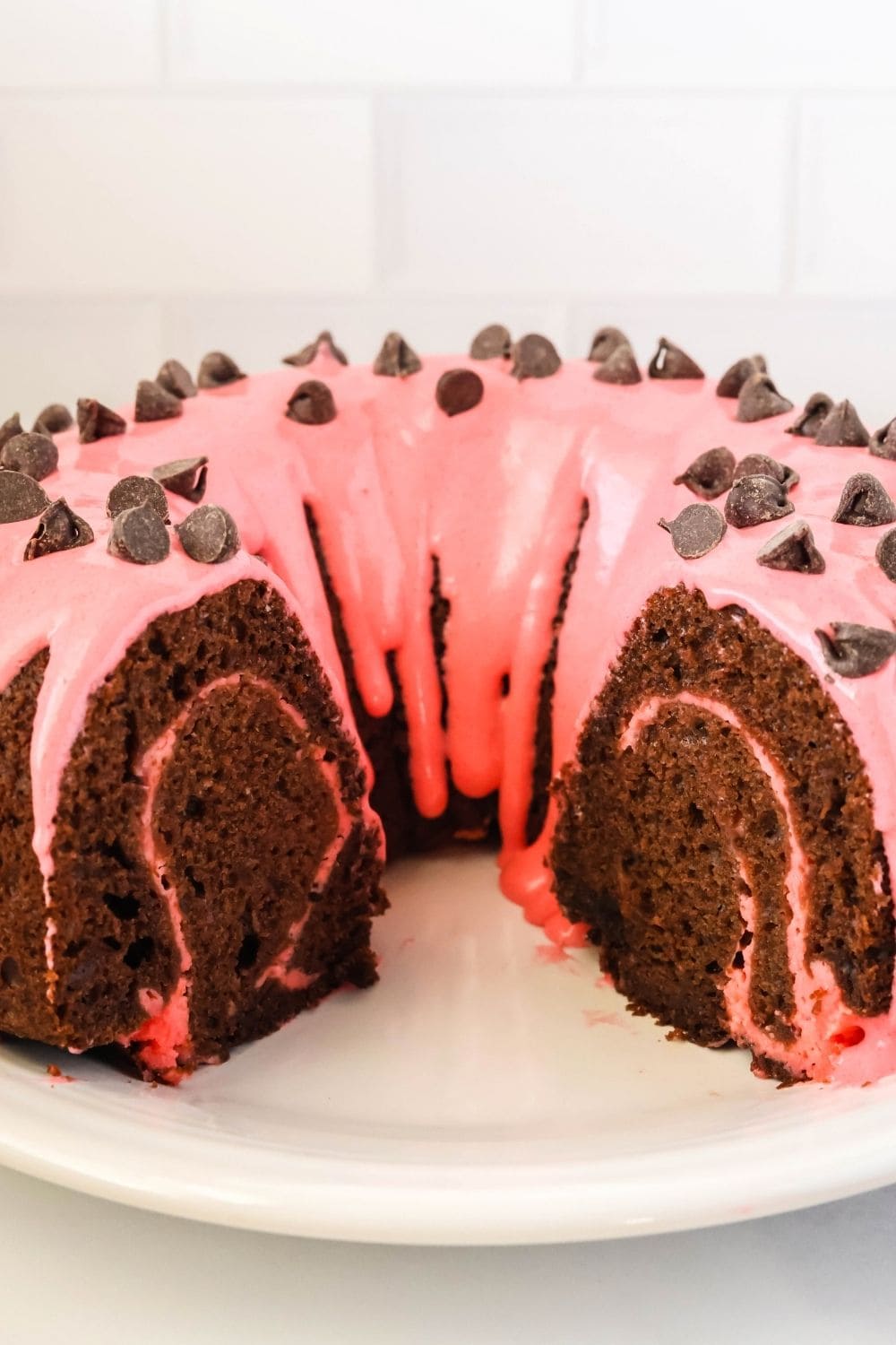 chocolate strawberry swirl bundt cake with a couple of slices removed, showing the strawberry swirl within the chocolate cake.