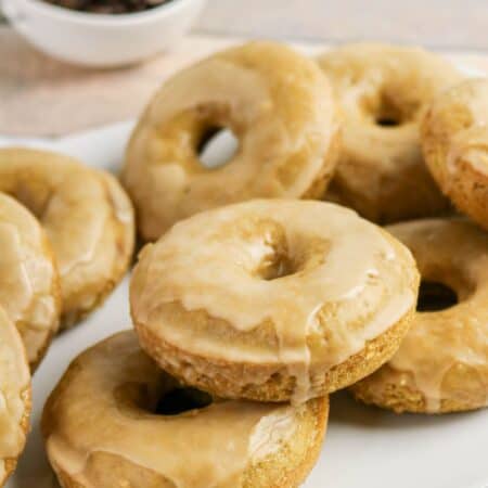 Several glazed coffee donuts served on a white platter.
