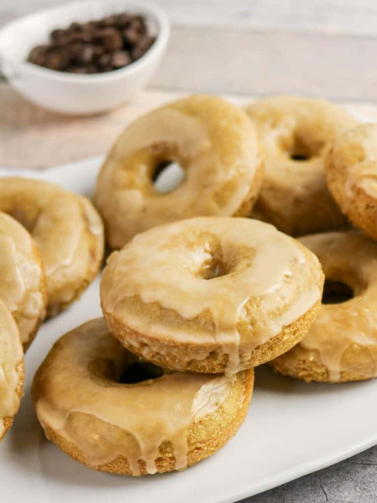 Several glazed coffee donuts served on a white platter.