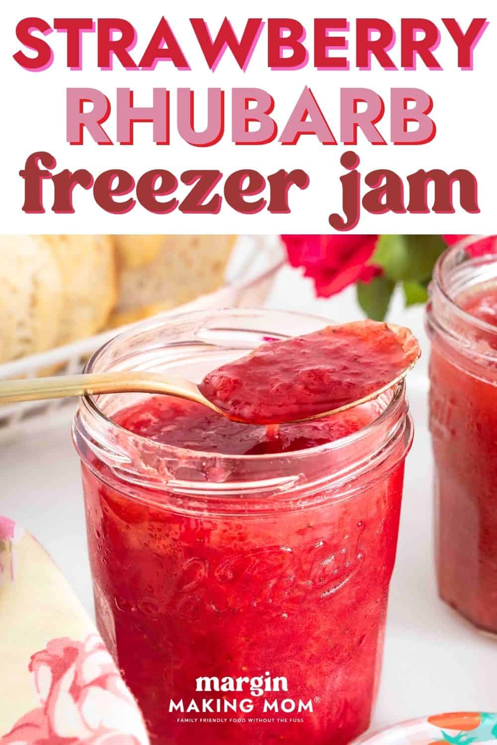 Strawberry rhubarb freezer jam in a glass jar with a spoon in it.