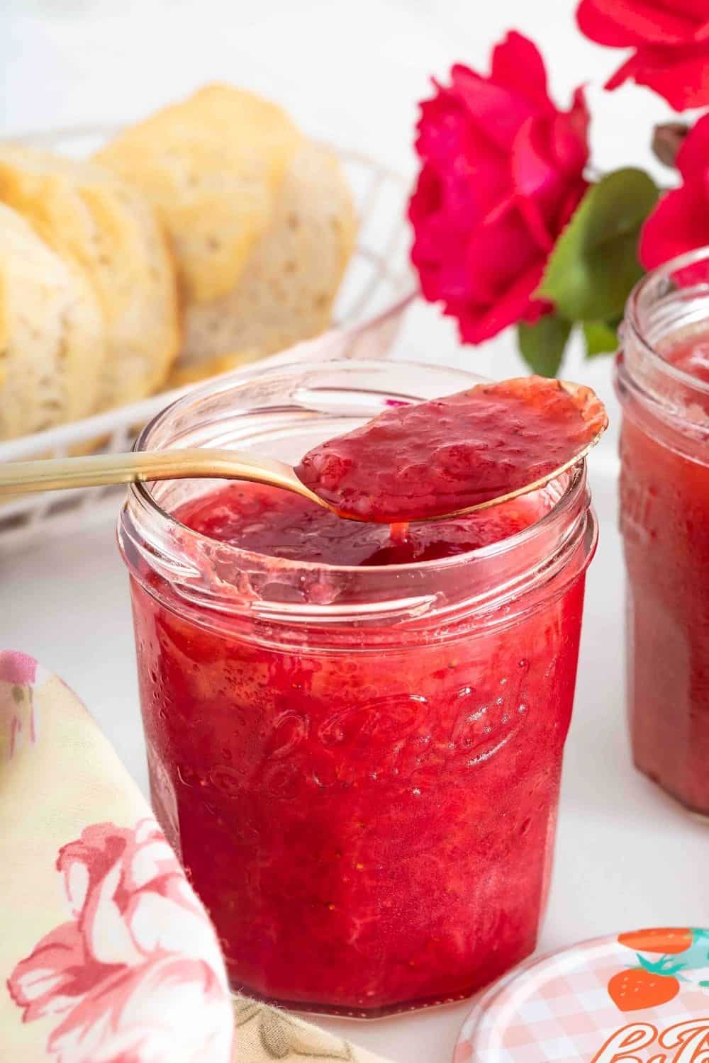 a glass jar of small batch strawberry rhubarb jam with a spoon in it.
