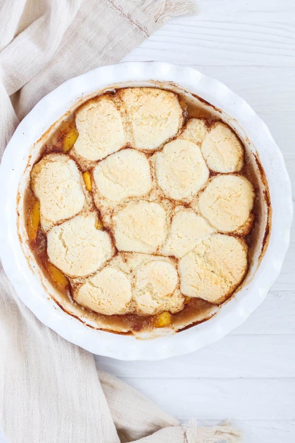 overhead view of a deep dish pie pan filled with freshly-baked canned peach cobbler.