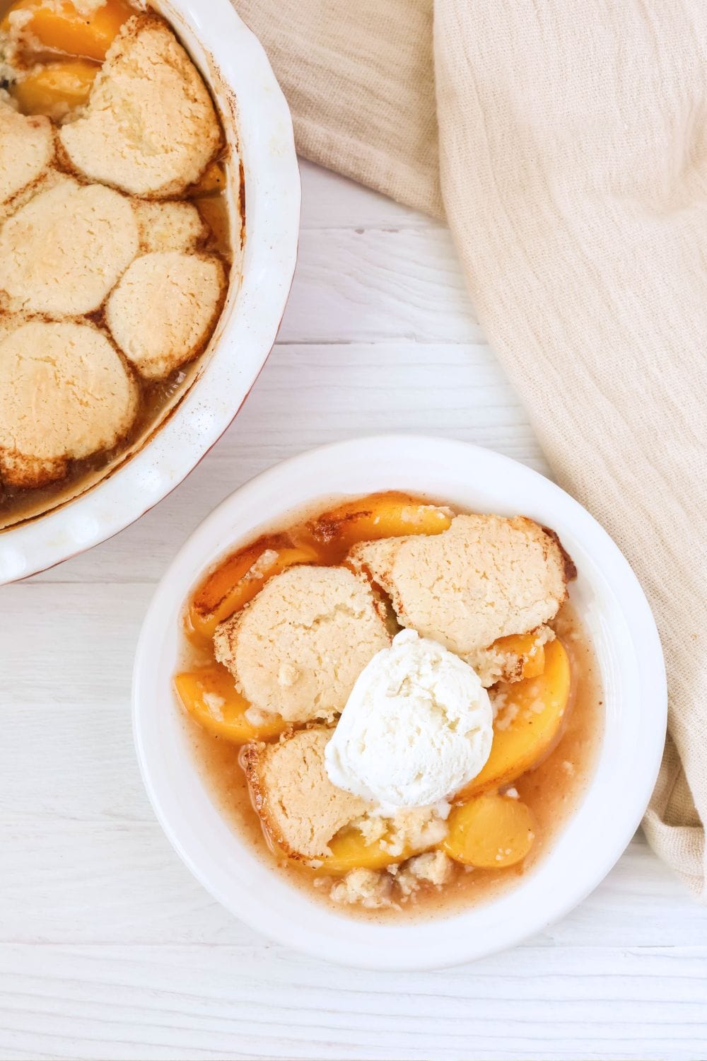 overhead view of a plate with a serving of Bisquick peach cobbler on it; the deep dish pie pan of remaining cobbler is next to the plate.