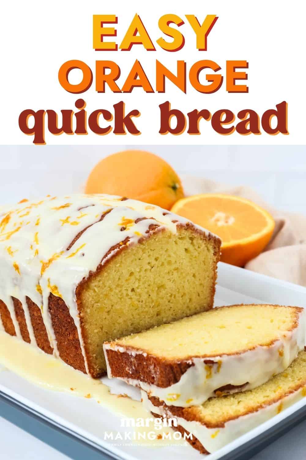 Sliced loaf of orange quick bread on a white platter, with fresh oranges in the background.