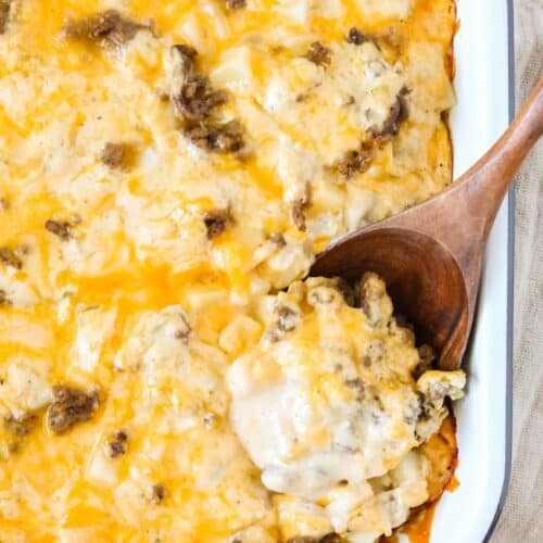 Baking dish of hobo casserole with a wooden spoon scooping out a serving.