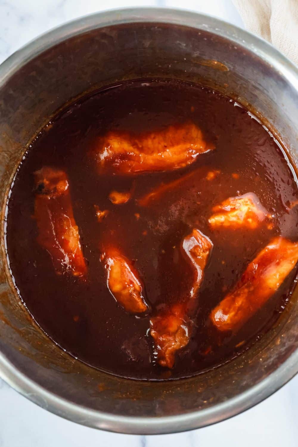 Moist country style ribs in BBQ sauce inside the insert pot of an Instant Pot pressure cooker.