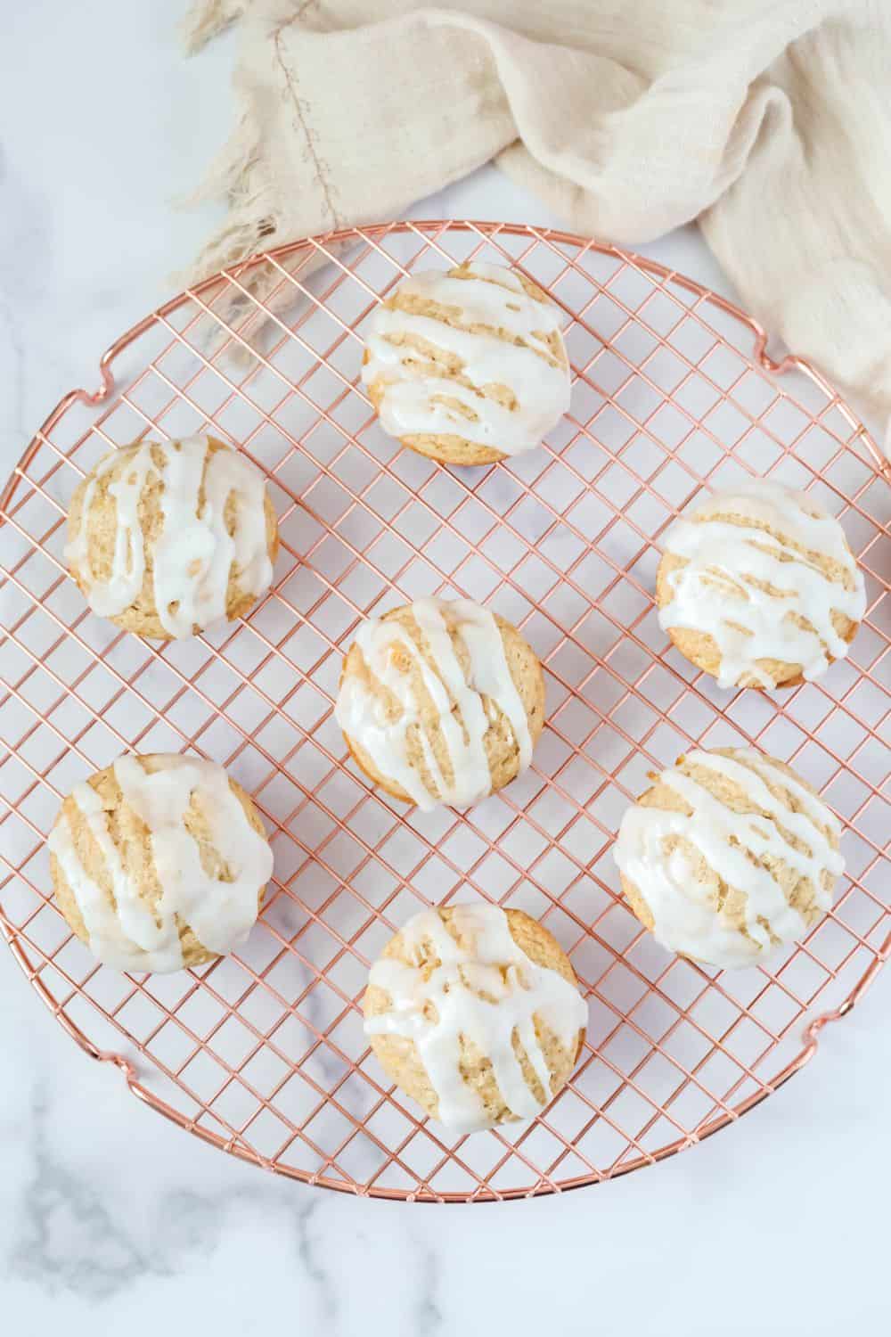 Overhead view of peach muffins with icing on a wire rack.