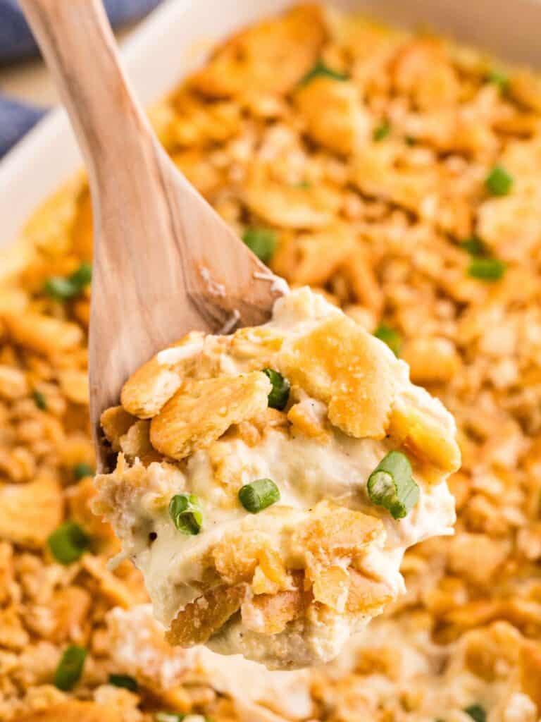 Serving spoon scooping Ritz cracker chicken casserole from the baking dish.