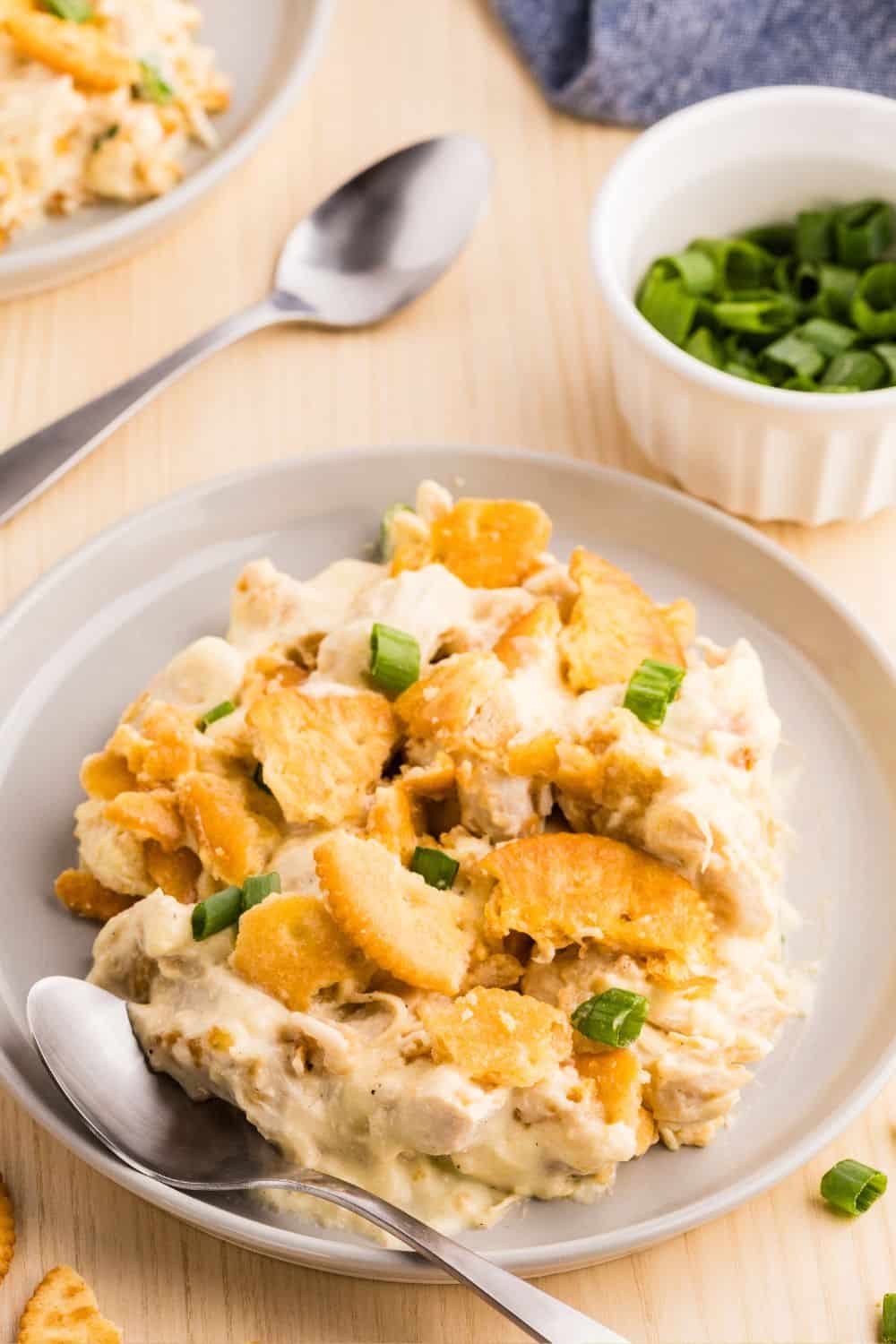 A serving of Ritz cracker chicken casserole made with mayonnaise and sour cream, served on a beige plate and garnished with sliced green onions.