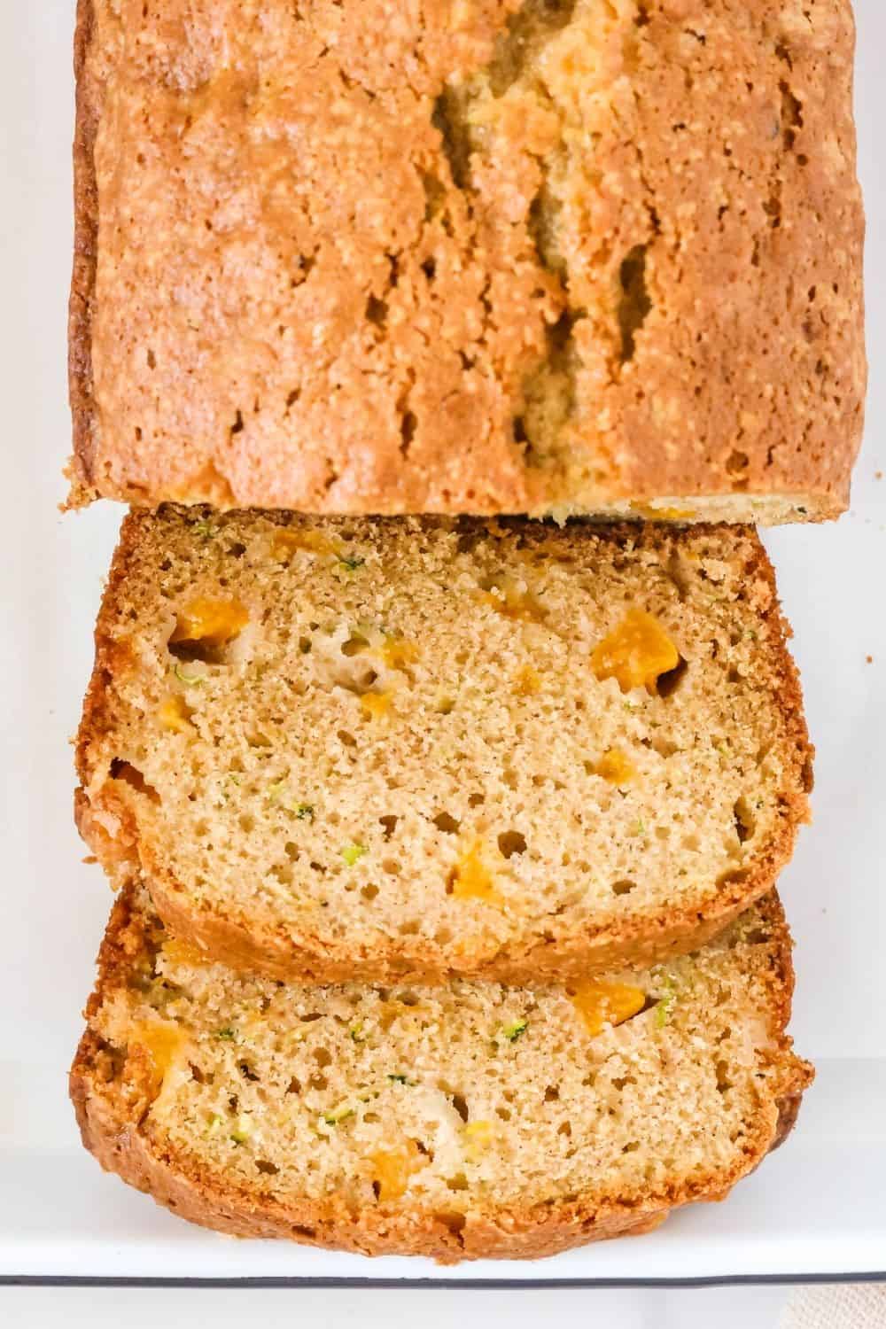 Overhead view of a sliced loaf of soft moist peach zucchini bread, showing the tender interior of the loaf in its slices.