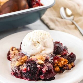 Bisquick cherry cobbler served on a white plate with a scoop of vanilla ice cream.