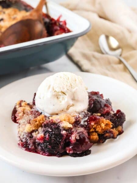 Bisquick cherry cobbler served on a white plate with a scoop of vanilla ice cream.
