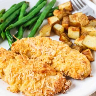 Two Bisquick chicken tenders served on a white plate with roasted potatoes and green beans.