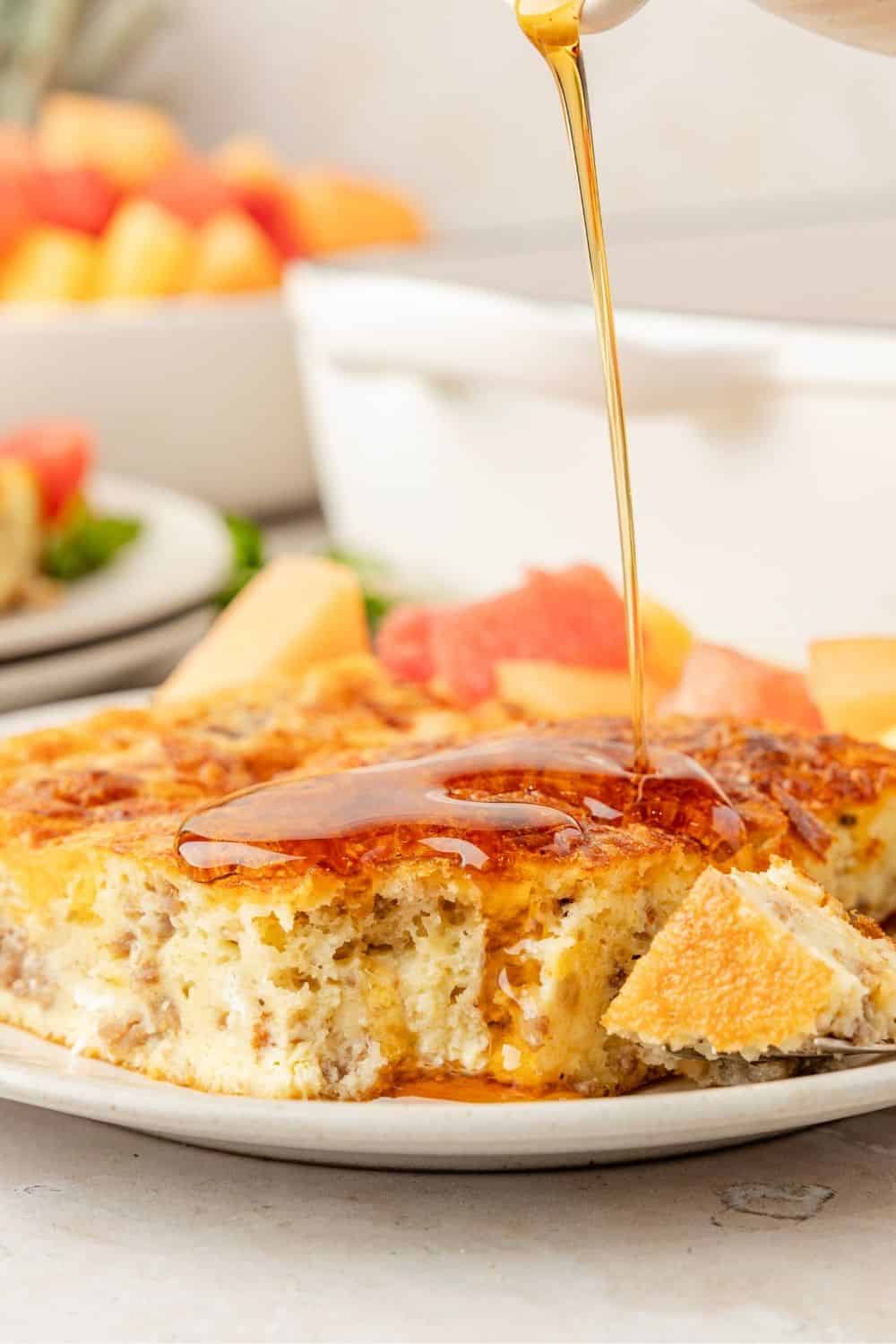 Bisquick breakfast casserole being drizzled with maple syrup.
