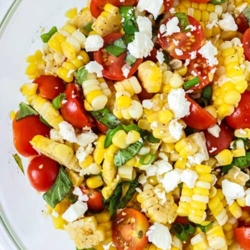 Corn and tomato salad served in a glass bowl.