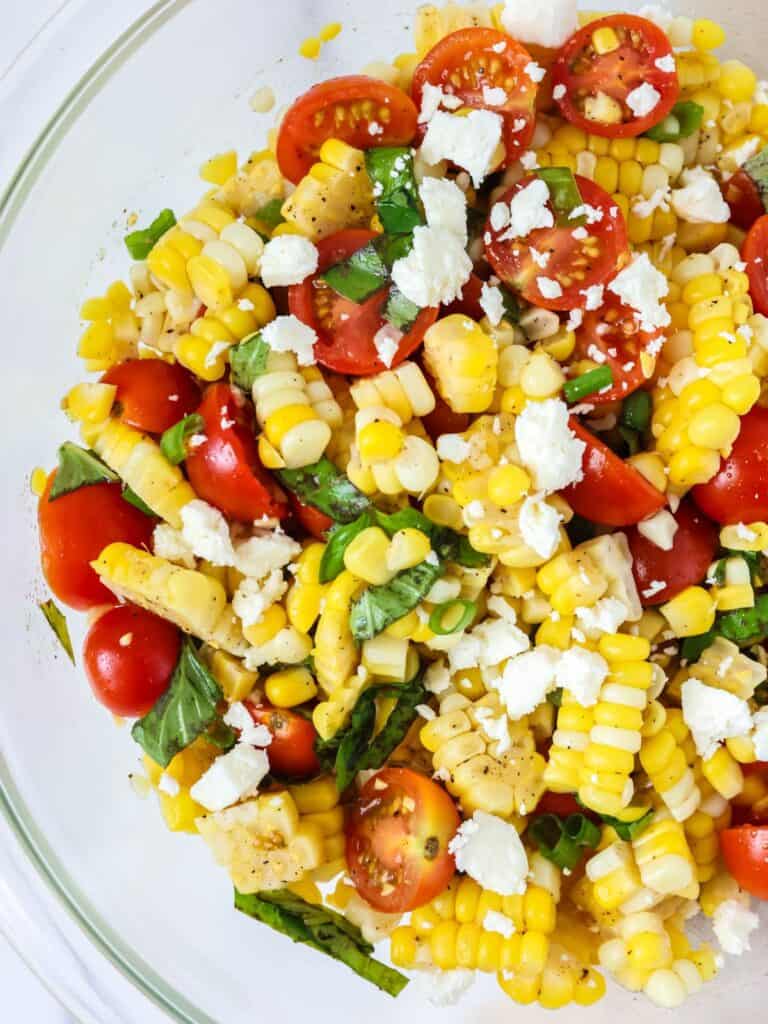 Corn and tomato salad served in a glass bowl.