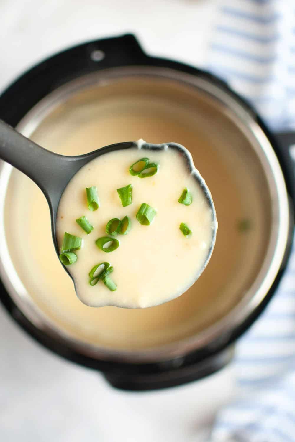A ladle scoops out creamy cauliflower soup from an Instant Pot pressure cooker.